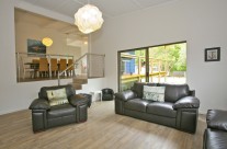 The living room has a comfy leather lounge, large flat screen television, and an ipod/ipad docking station.
